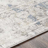 Close-up of the Holcombe Area Rug showing its charcoal, cream, and gray traditional pattern and machine-woven texture. Texture