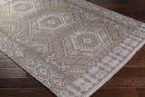 Close-up of Honeydew Area Rug. Hand-woven rug with cream, light gray, brown, and sky blue geometric pattern. Corner