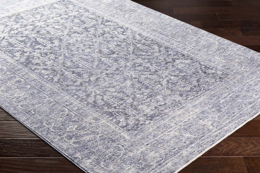 Close-up of Housatonic Area Rug in denim and white with a traditional oriental pattern on dark wood floors. Corner