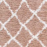 Close-up of the Hornsby Area Rug. Dusty pink shag rug with a geometric off-white diamond pattern. Soft texture. Swatch