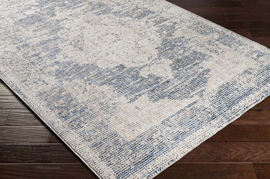 Close-up of Herricks Denim Medallion Area Rug showing cream, denim, and beige colors on a dark wood floor. Corner