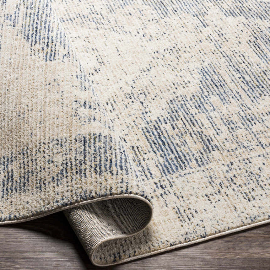 Close-up of the Herricks Denim Medallion Area Rug showing its cream, denim, and light beige colors and textured, woven design. Fold