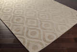 Close-up of the Hundred Area Rug. Tan wool rug with a contemporary, geometric teardrop and circle pattern. Corner