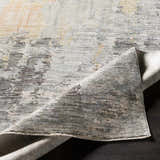 Close-up of the Hustontown Carved Statement Rug, showcasing its carved texture and blend of gray, ivory, and saffron colors. Fold
