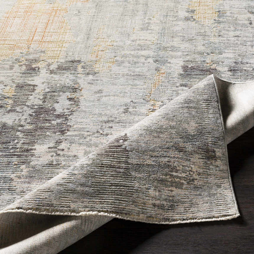 Close-up of the Hustontown Carved Statement Rug, showcasing its carved texture and blend of gray, ivory, and saffron colors. Fold