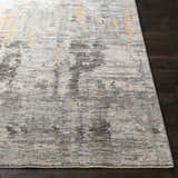 Close-up of the Hustontown Carved Statement Rug. Abstract pattern in blue, charcoal, sage, gray, and ivory on dark wood floor. Front