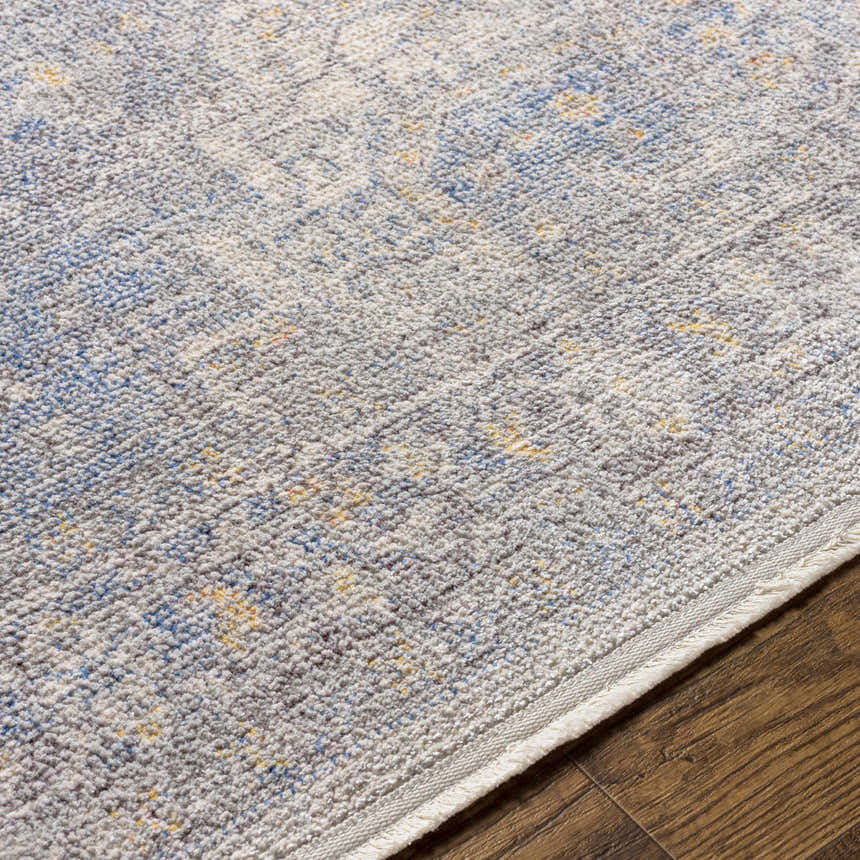 Close-up of Akio Blue Area Rug showing its texture, light gray, pale blue, and mustard colors on dark wood flooring. Texture