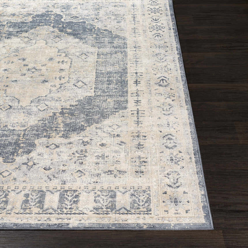 Close up of the traditional Indore Area Rug in black, charcoal, gray, off white, and tan on dark wood flooring. Front