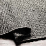 Close-up of the hand woven Innisfail Area Rug. Black and medium gray cotton and recycled PET yarn texture. Fold