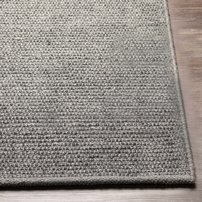 Close-up of the hand woven Innisfail Area Rug. Medium gray and black cotton rug with a textured, solid striped design. Front