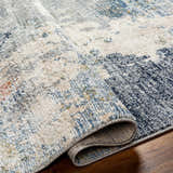 Close-up of the Iryna Area Rug showing the charcoal, gray, and brown contemporary pattern and woven texture. Fold