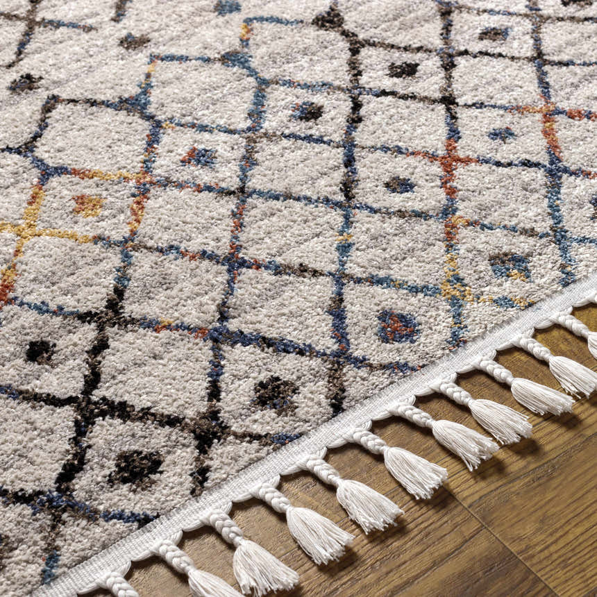 Close-up of the Itogon Area Rug. Geometric pattern in black, brick red, burnt orange, and teal with fringe detail. Texture
