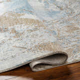 Close-up of the Jaela Thick Luxe Area Rug showing its light gray, brown, and blue contemporary pattern and plush texture. Fold