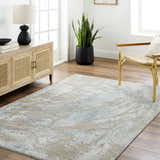 Living room scene with a Jaela Thick Luxe Area Rug in gray, brown, and blue tones. The rug is styled with a wood cabinet and woven chair. Roomscene-Rectangle