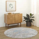 Entryway scene with a round Jaela Thick Luxe Area Rug in light gray, blue, and brown tones, complementing the wood cabinet and floors. Roomscene-Round