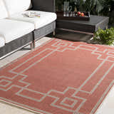 Outdoor patio scene with brick red Jarrell Area Rug, light beige geometric pattern, and white cushioned seating. Roomscene-Rectangle