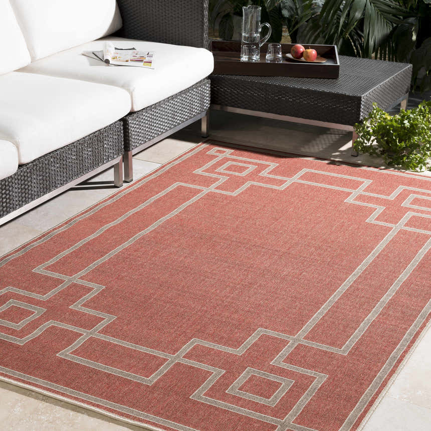Outdoor patio scene with brick red Jarrell Area Rug, light beige geometric pattern, and white cushioned seating. Roomscene-Rectangle