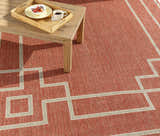 Brick red Jarrell Area Rug with light beige geometric pattern under a wood coffee table on a patio. Styleshot