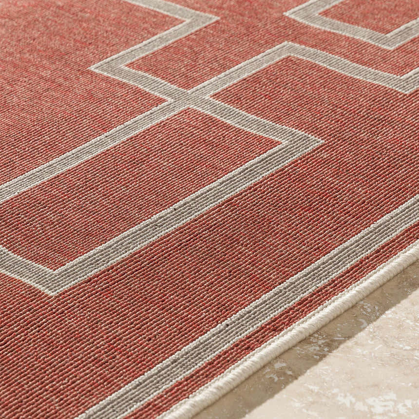 Close-up of the Jarrell Area Rug showing brick red olefin and light beige geometric pattern. Texture