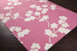 Close-up of the Johnstown Area Carpet. Light beige floral pattern on a rose, hand woven 100% wool rug. Corner