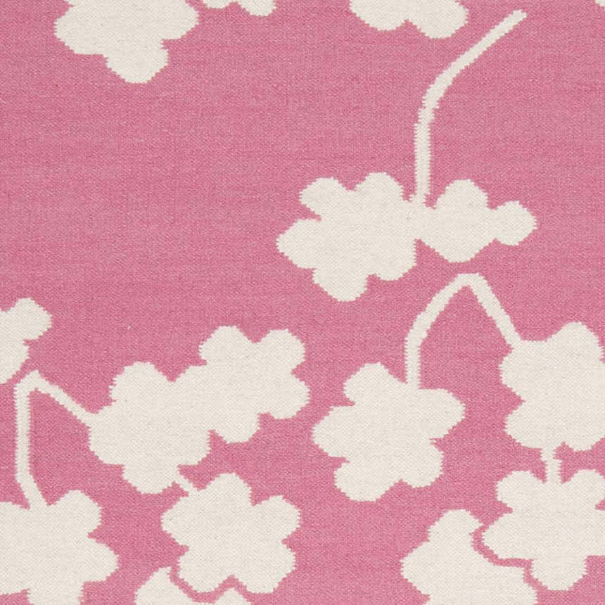 Close-up of the Johnstown Area Carpet. Light beige floral design on a rose pink, hand-woven wool rug. Swatch