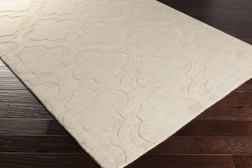 Close up of the tan, hand loomed wool Kake Carpet, featuring a subtle contemporary quatrefoil pattern. Corner
