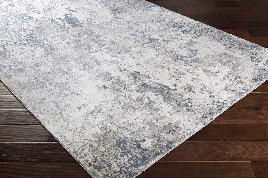 Close-up of the Kanahooka Area Rug. Contemporary design in charcoal, dark blue, beige, and gray on dark wood floors. Corner