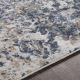 Close-up of the Kanahooka Area Rug showing its contemporary charcoal, blue, beige, and gray abstract pattern and soft texture. Texture