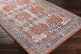 Close-up of the Kangundo Washable Area Rug showing its red, cream, and blue bohemian pattern on a dark wood floor. Corner