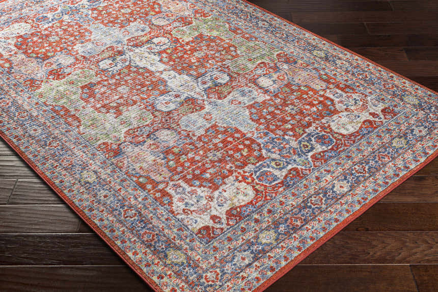 Close-up of the Kangundo Washable Area Rug showing its red, cream, and blue bohemian pattern on a dark wood floor. Corner
