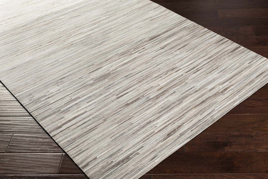 Close up of the Karabar Premium Area Rug showing beige, brown, and silver gray tones on dark wood floors. Corner