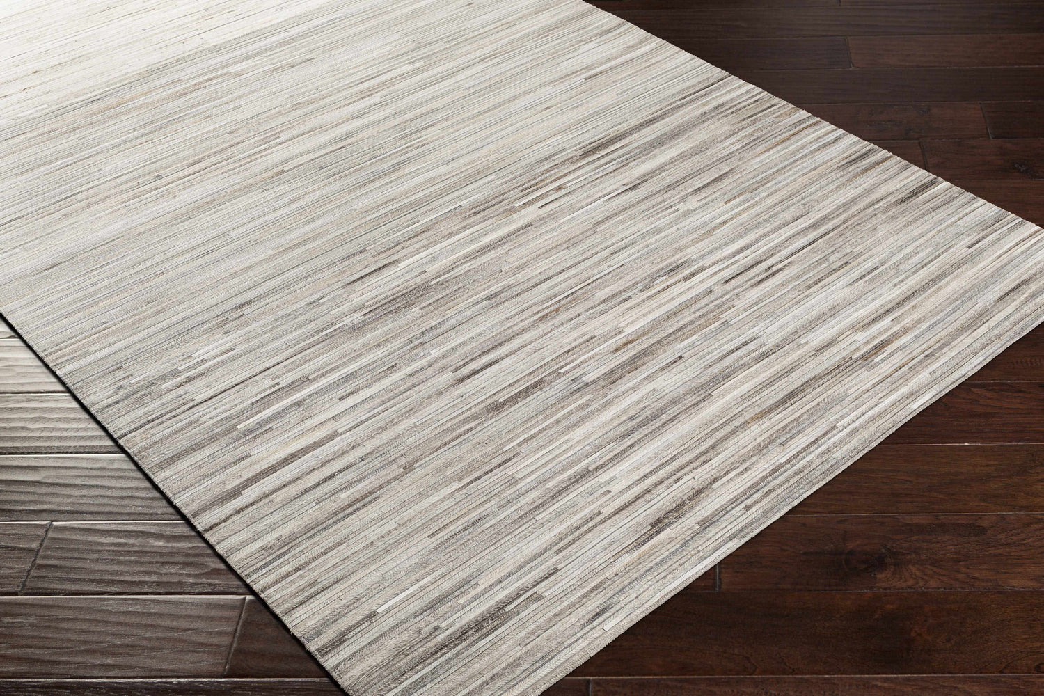 Close up of the Karabar Premium Area Rug showing beige, brown, and silver gray tones on dark wood floors. Corner
