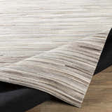Close-up of the Karabar Premium Area Rug showing beige, brown, and gray hair on hide strips. Hand-crafted rectangular rug. Fold