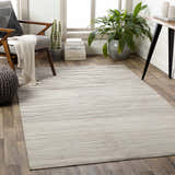 Living room scene with a beige Karabar Premium Area Rug, gray chair, and potted plant. Roomscene-Rectangle