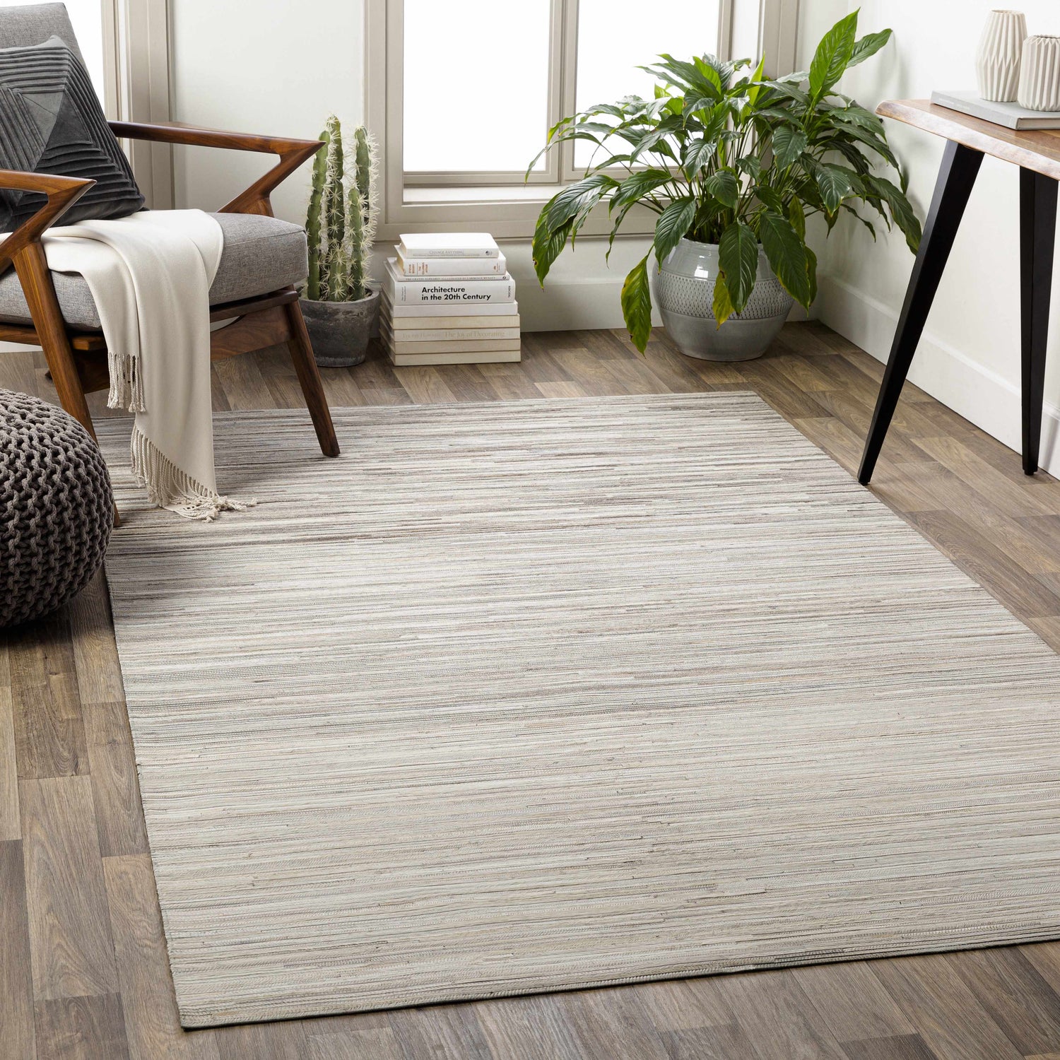 Living room scene with a beige Karabar Premium Area Rug, gray chair, and potted plant. Roomscene-Rectangle