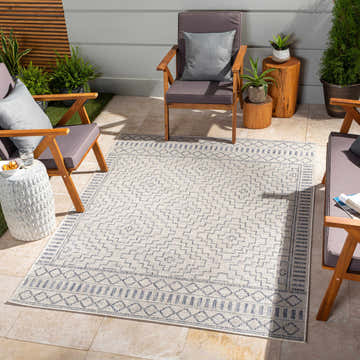 Coastal patio scene with bone and dark gray Kabala Indoor Outdoor Rug, wood chairs, and plants. Roomscene-Rectangle