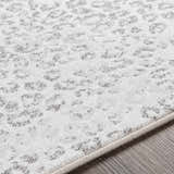 Close-up of the Keenes Leopard Print Area Rug showing charcoal spots on a cream and light gray textured surface. Texture
