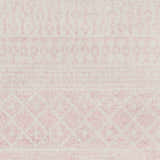 Close-up of the Constantin Blush Area Rug. Features a subtle bohemian pattern in blush and light gray tones. Texture
