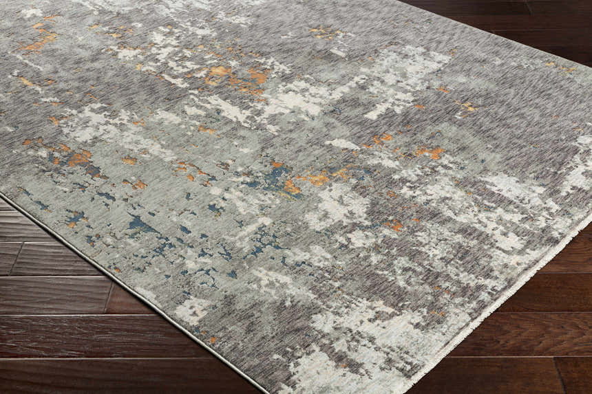 Close-up of the Kenedy Carved Statement Carpet in gray, ivory, blue, and orange on a dark wood floor. Abstract, contemporary style. Corner