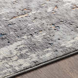 Close-up of the Kenedy Carved Statement Carpet in gray, ivory, and blue with a contemporary abstract pattern. Texture