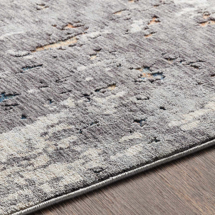 Close-up of the Kenedy Carved Statement Carpet in gray, ivory, and blue with a contemporary abstract pattern. Texture