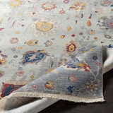 Close-up of the Kernersville Area Rug featuring a traditional floral pattern in blue, orange, and gray tones. Fold
