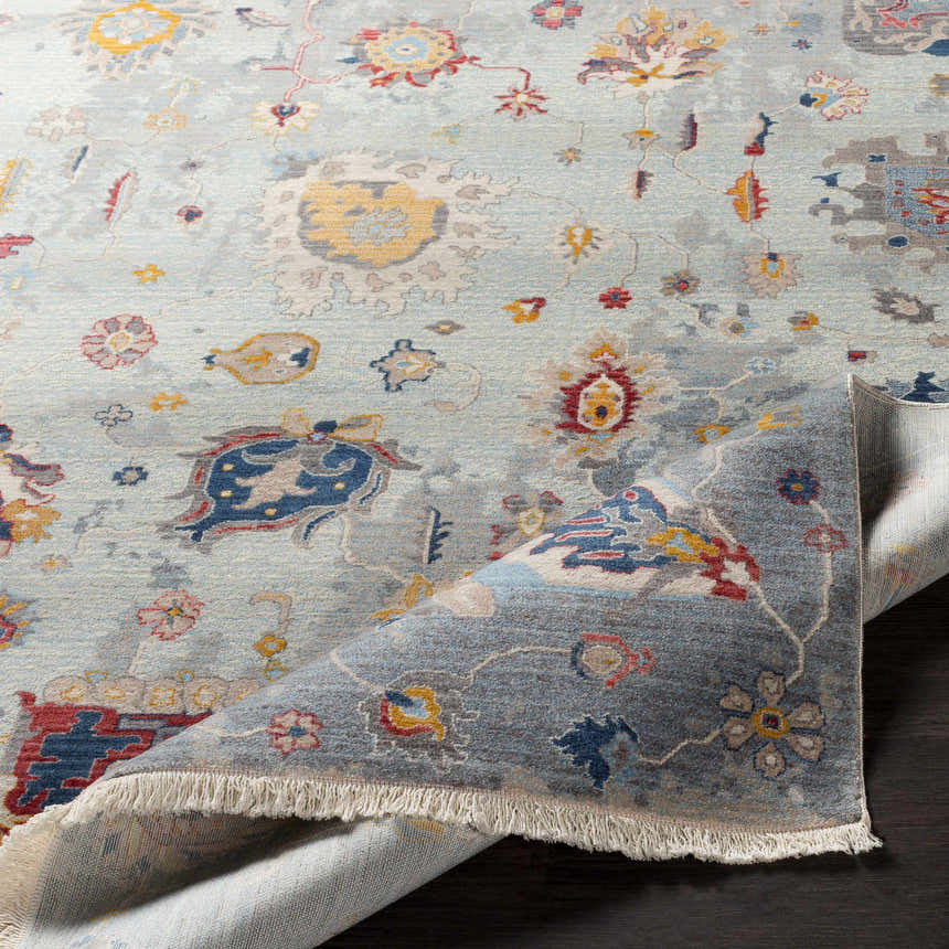 Close-up of the Kernersville Area Rug featuring a traditional floral pattern in blue, orange, and gray tones. Fold
