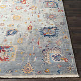 Close-up of the Kernersville Area Rug showing its blue, burnt orange, and gray traditional floral pattern and fringe. Front
