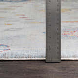 Close up of Kernersville Area Rug showing light beige, blue, and rose colors. Ruler shows rug thickness. Pile