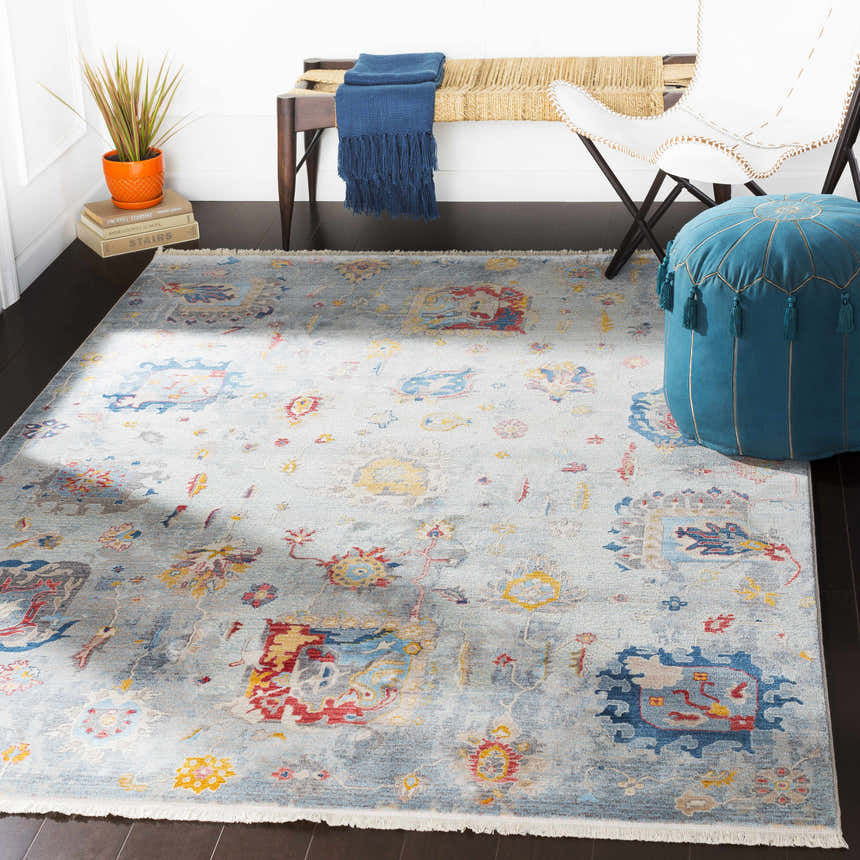 Entryway scene with a Kernersville Area Rug, blue ottoman, white chair, and wooden bench with a blue throw. Roomscene-Rectangle