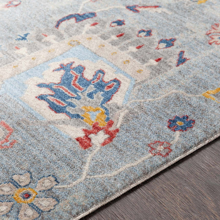 Close-up of the Kernersville Area Rug, showcasing its blue, gray, and burnt orange vintage-inspired floral pattern. Texture