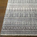 Close-up of the Kiara Area Rug, a hand-knotted wool rug with a black and light gray geometric pattern on a wood floor. Front