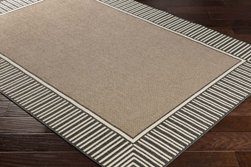 Close-up of the Kidron Area Rug; beige center with a black and beige striped border on dark wood flooring. Corner