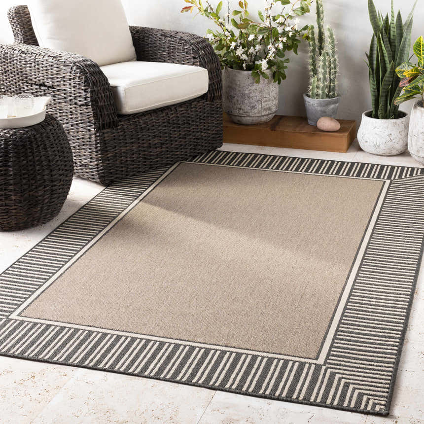 Patio scene with a beige Kidron Area Rug, black and white striped border, and wicker furniture. Roomscene-Rectangle